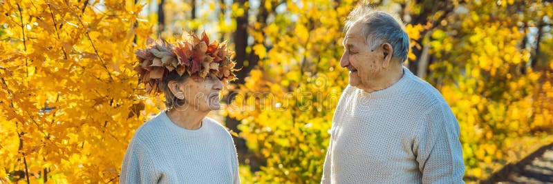 Viejos pares felices que se divierten en el parque del otoño Hombre mayor que lleva una guirnalda de las hojas de otoño a su BAND imagen de archivo Viejos pares felices que se divierten en el parque del otoño Hombre mayor que lleva una guirnalda de las hojas de otoño a su BAND imagen de archivo