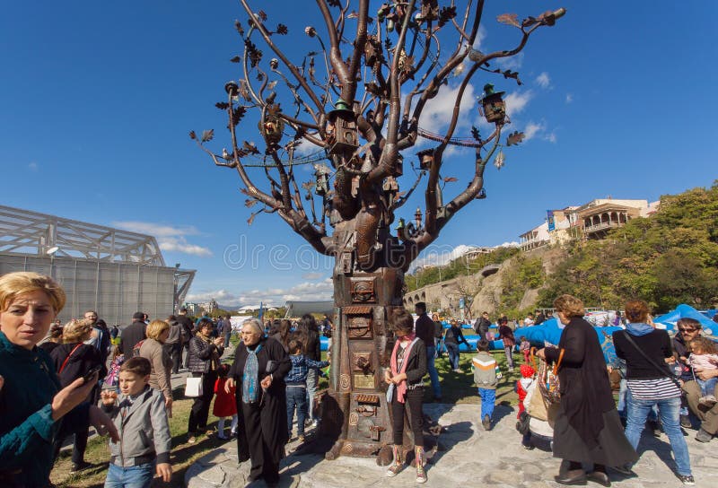 Viele Leute mit den Familien, die in Rike gehen, parken mit Metallbaum des Lebens lizenzfreie stockbilder Viele Leute mit den Familien, die in Rike gehen, parken mit Metallbaum des Lebens lizenzfreie stockbilder