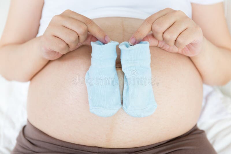Close up of a pregnant belly with a pair of blue socks. Close up of a pregnant belly with a pair of blue socks.