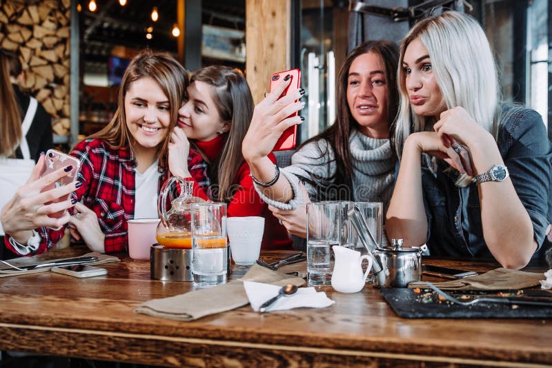 Vier Freunde, die durch die Tabelle im Café sitzen und selfie auf Smartphone machen stockfotos Vier Freunde, die durch die Tabelle im Café sitzen und selfie auf Smartphone machen stockfotos