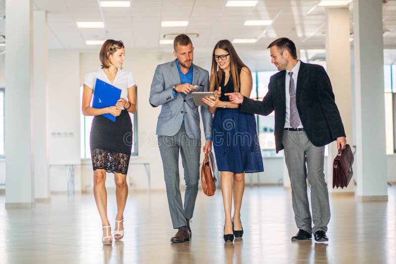 Vier Geschäftsleute, die in Bürolobby sprechen und gehen lizenzfreie stockfotografie Vier Geschäftsleute, die in Bürolobby sprechen und gehen lizenzfreie stockfotografie