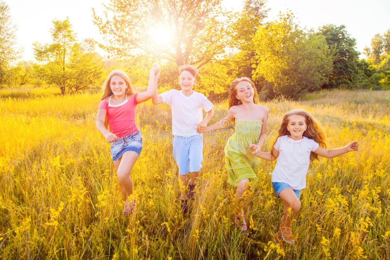 Vier glückliche schöne Kinder, die am schönen Sommertag zusammenrücken spielend laufen lizenzfreie stockfotografie Vier glückliche schöne Kinder, die am schönen Sommertag zusammenrücken spielend laufen lizenzfreie stockfotografie