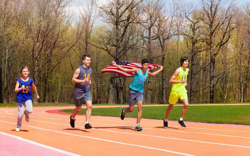 Vier jonge sprinters die Amerikaanse vlag op spoor golven stock foto Vier jonge sprinters die Amerikaanse vlag op spoor golven stock foto