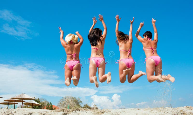 Vier meisjes die op het strand springen stock foto's Vier meisjes die op het strand springen stock foto's