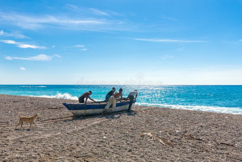 Vier nicht identifizierte lokale Fischer, die ihr Boot zum Meer drücken und für die Fischerei, Hund folgt ihnen sich vorbereiten lizenzfreie stockfotografie
