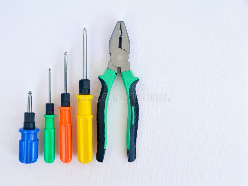 Vier schroevedraaiers van verschillende grootte met blauwe, groene, rode en gele handvatten op houten tablePliers en vier schroev stock foto Vier schroevedraaiers van verschillende grootte met blauwe, groene, rode en gele handvatten op houten tablePliers en vier schroev stock foto