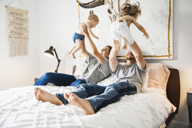 Vierköpfige Familie mit dem Baby, das Spaß auf Bett hat lizenzfreie stockfotos Vierköpfige Familie mit dem Baby, das Spaß auf Bett hat lizenzfreie stockfotos