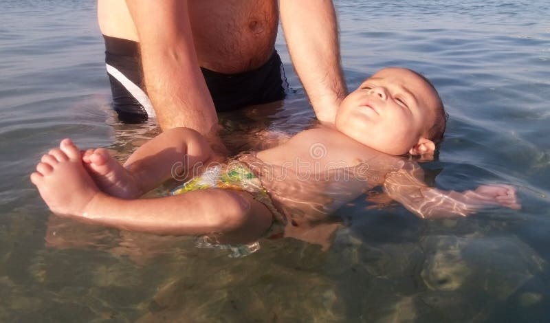 Viermonatliche alte Schwimmen des ersten Males des Babys im Meer lizenzfreies stockfoto Viermonatliche alte Schwimmen des ersten Males des Babys im Meer lizenzfreies stockfoto