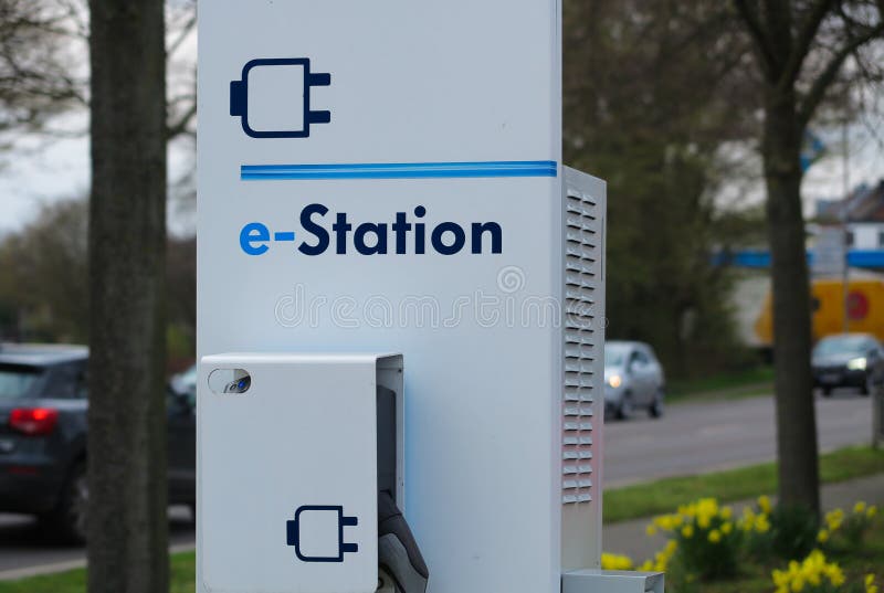 VIERSEN TYSKLAND - MARS 27 2019: Stäng sig upp av uppladdningsstationen för elbilar som omges av gula tulpan royaltyfri bild VIERSEN TYSKLAND - MARS 27 2019: Stäng sig upp av uppladdningsstationen för elbilar som omges av gula tulpan royaltyfri bild