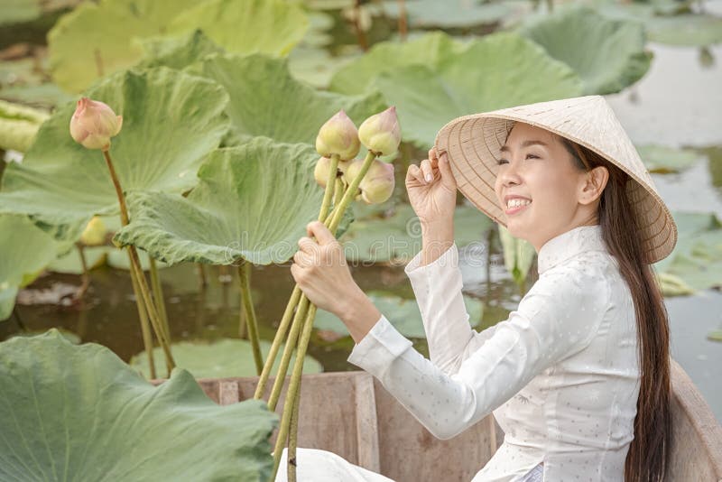 Vietnamees wijfje op een houten boot die lotusbloembloemen verzamelen Aziatische vrouwen die op houten boten zitten om lotusbloem royalty-vrije stock fotografie Vietnamees wijfje op een houten boot die lotusbloembloemen verzamelen Aziatische vrouwen die op houten boten zitten om lotusbloem royalty-vrije stock fotografie