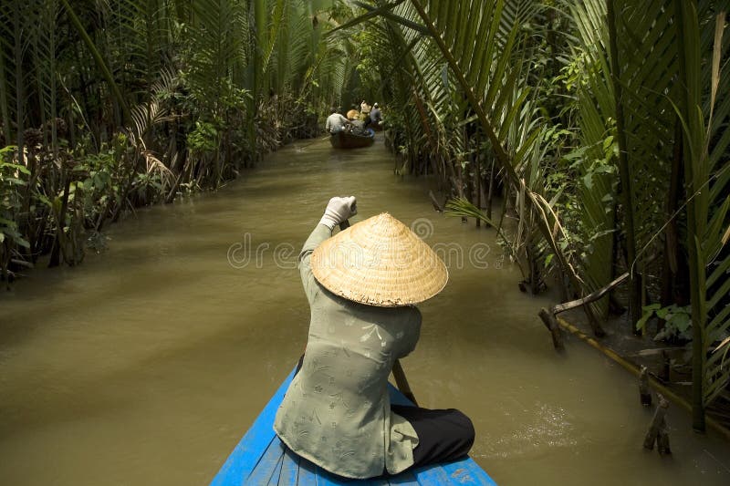 Vietnamesische Frau, die ein Boot rudert stockbild Vietnamesische Frau, die ein Boot rudert stockbild