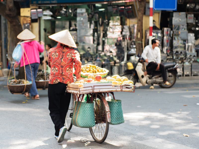Vietnamesiska gatuförsäljare agerar och säljer deras grönsaker och fruktprodukter i Hanoi, Vietnam