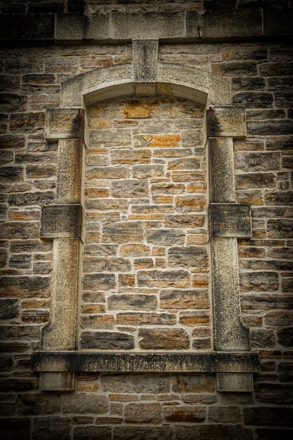Detail of the masonry work of an ancient stoned up window frame architectural detail on a stone, Gothic style building. Detail of the masonry work of an ancient stoned up window frame architectural detail on a stone, Gothic style building.