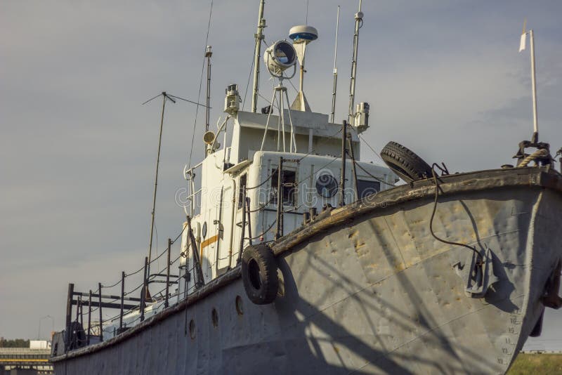 Vieux long bateau rouillé ancré au pilier photos stock Vieux long bateau rouillé ancré au pilier photos stock