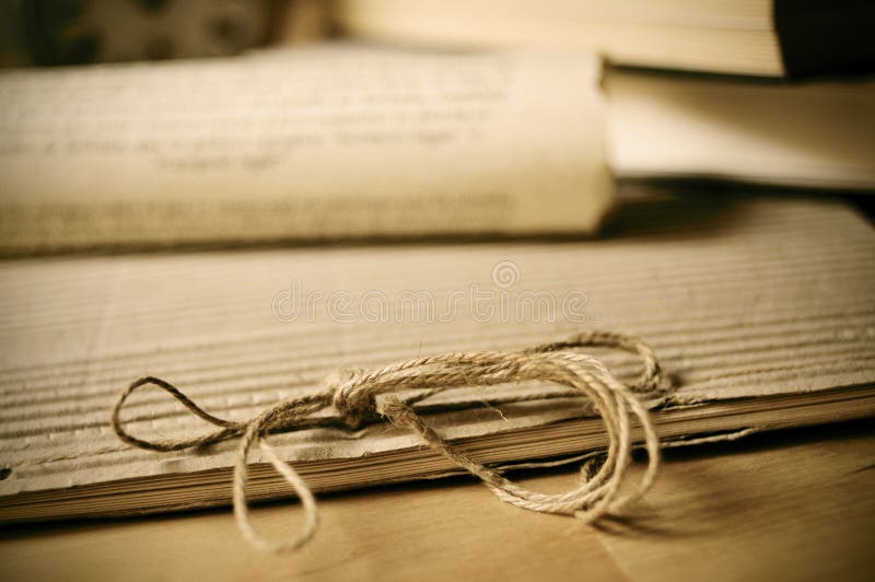 Detail of an old notepad and some old rolled papers on a wooden table. Detail of an old notepad and some old rolled papers on a wooden table