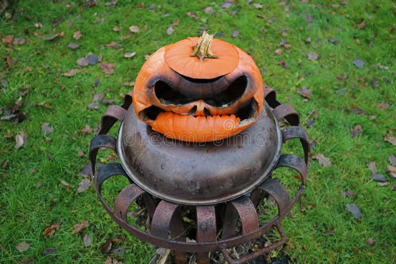 Vieux potiron brûlé de Halloween sur le panier de feu photos stock Vieux potiron brûlé de Halloween sur le panier de feu photos stock