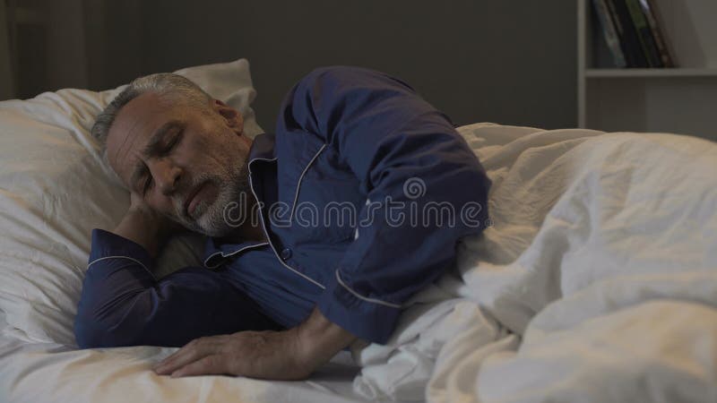 Vieux se situer masculin dans son lit et sommeil, temps de rétablissement et sommeil sain, nuit photos libres de droits Vieux se situer masculin dans son lit et sommeil, temps de rétablissement et sommeil sain, nuit photos libres de droits