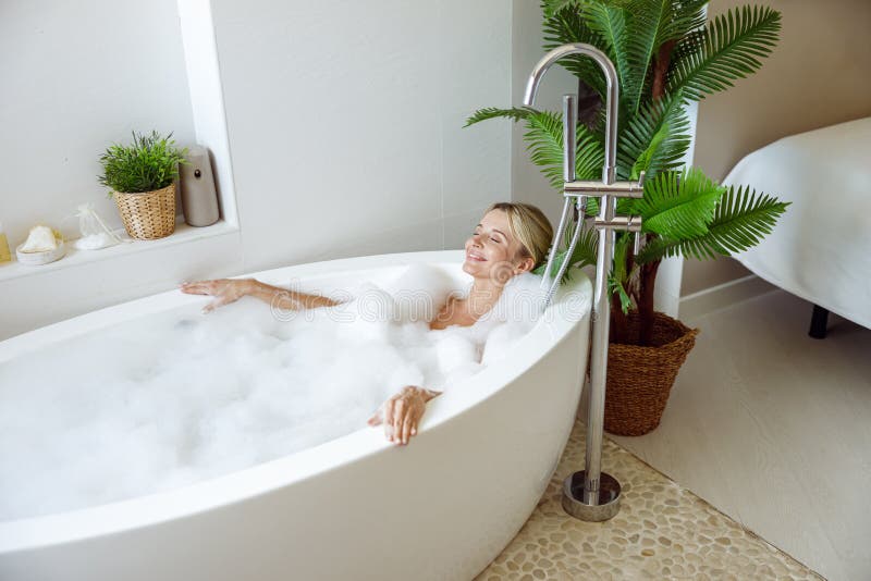 View from above on young beautiful female lying in warm bath, smiling and resting in spa.