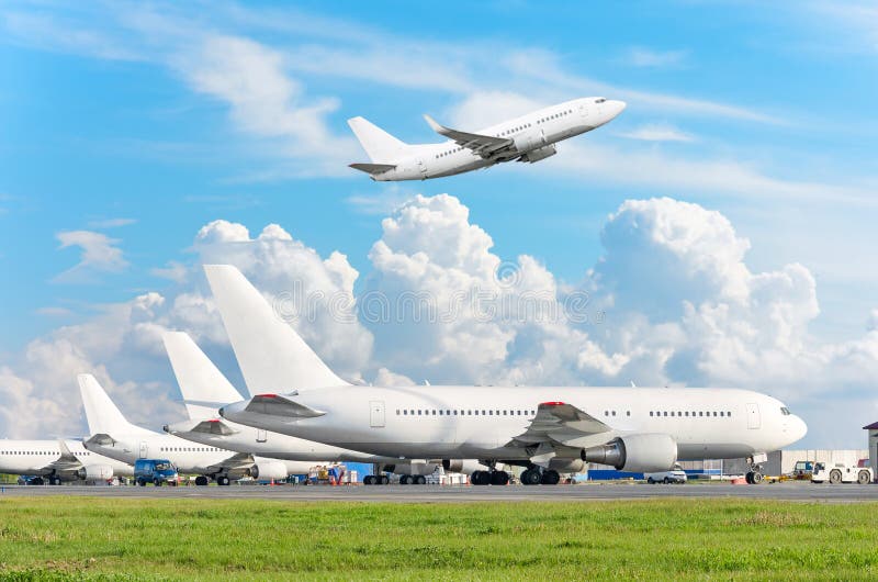 View of the airport aircraft parking at the terminal, and a plane taking off in the sky with clouds.