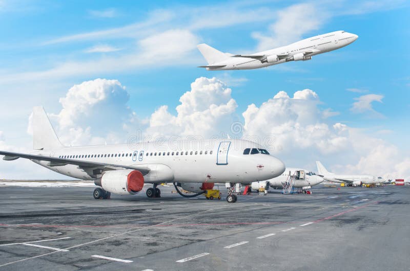 View of the airport aircraft parking at the terminal, and a plane taking off in the sky with clouds.