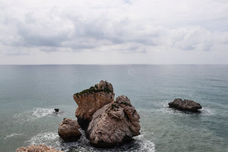 View on AphroditeÂ´s rock from bigger hill on Petra tou romiou beach. Incredible clear water in mediterranean sea with cloudy sky