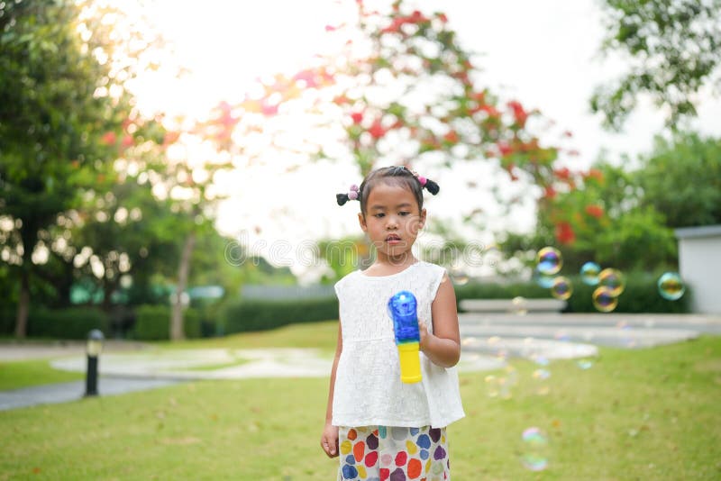View of an Asian Girl Shooting Bubbles while Standing I the Park Stock