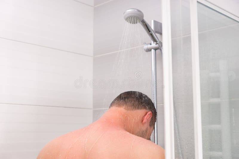 View from the back on a young man taking a shower