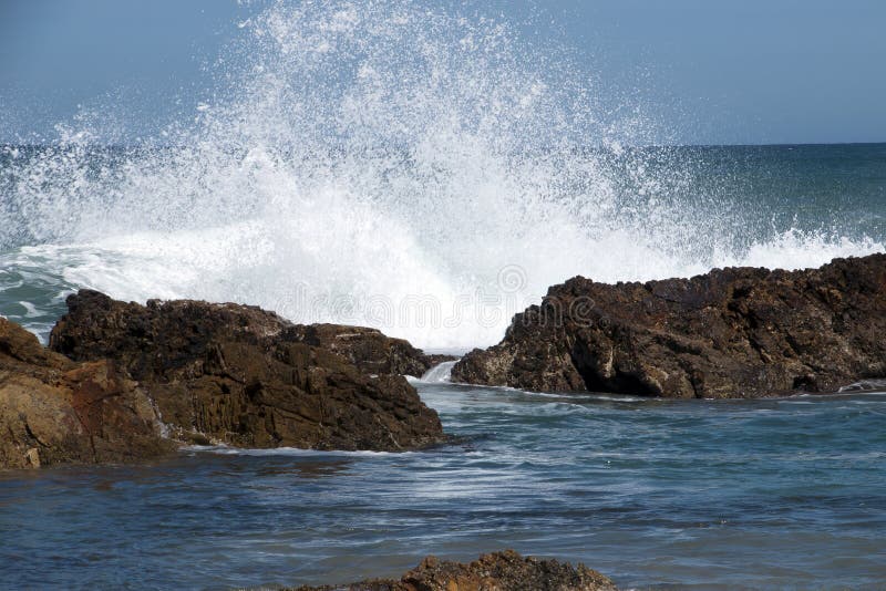 View from beach of horizon and waves breaking over rocky outcrops