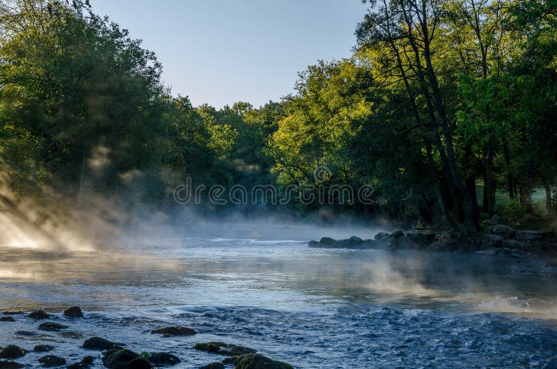 View of a beautiful landscape, with trees, water, morning light and mist.