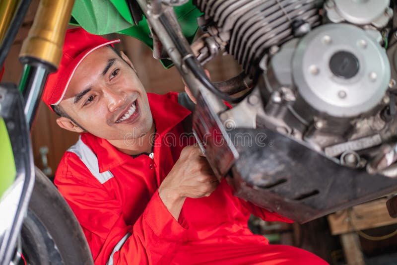 View from below of a mechanic using a box wrench to remove a motorcycle exhaust bolt