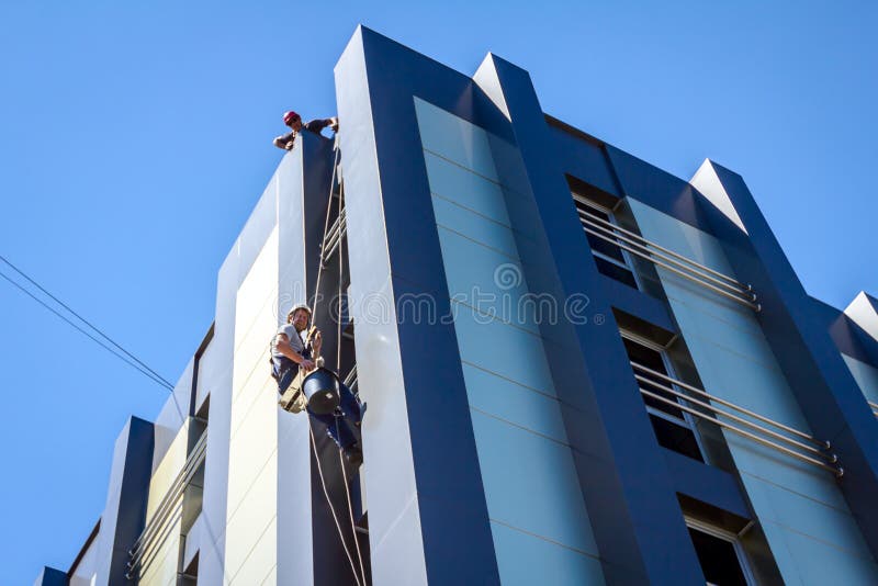 Industrial climber is washing, cleaning window of a modern office building