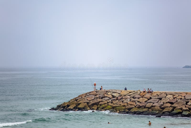 View of a big seawall on atlantic ocean and people enjoying the view and fishing stock images View of a big seawall on atlantic ocean and people enjoying the view and fishing stock images