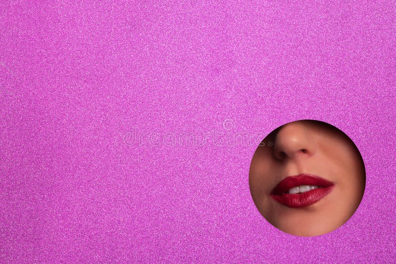 View of bright lips through hole in shimmer violet paper background. Make up artist, beauty concept. Ready to new year party. Banner, business.