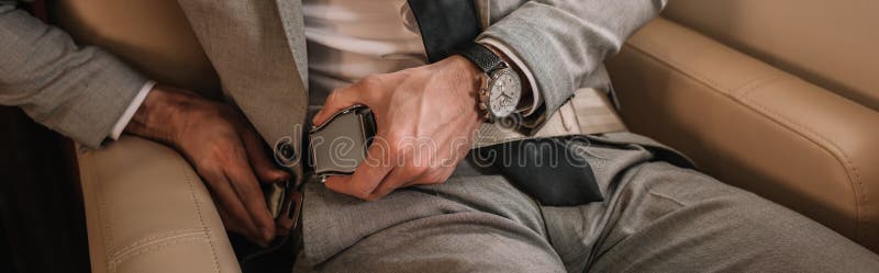 View of businessman fastening safety belt while sitting in private plane, panoramic shot