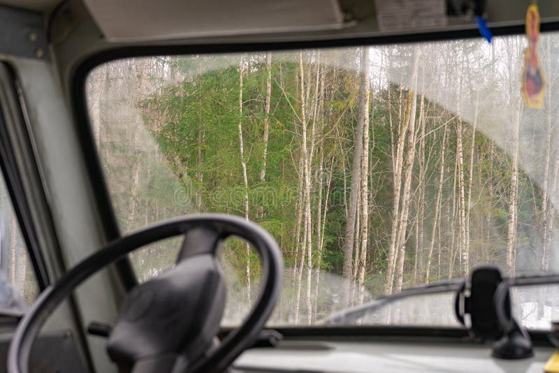 The view from the car through the dirty windshield of the forest. View from the drivers seat of the truck