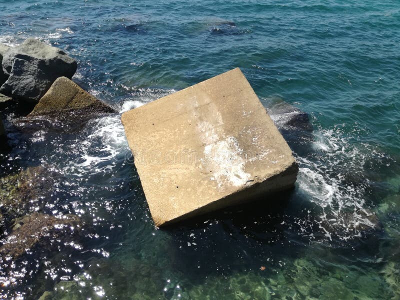 View of Cement Block in the Sea Water Illuminated by the Sun Stock