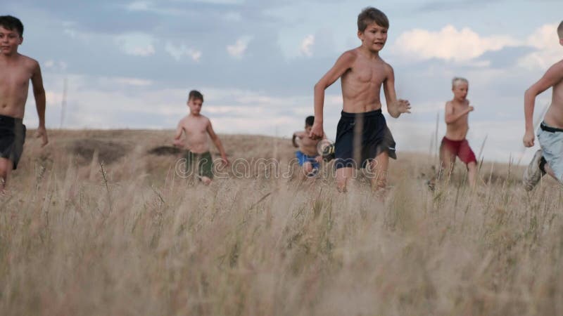 A view of children, competing in running in a field with yellow grass
