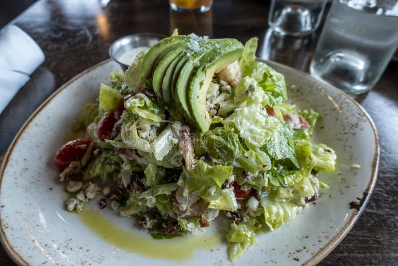 View of a decadent, Dungeness crab and avocado salad on a white and gold plate inside an upscale restaurant