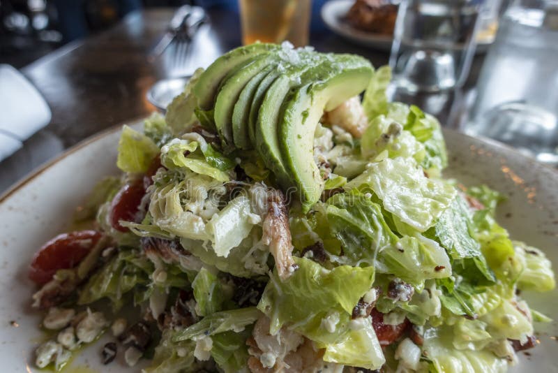 View of a decadent, Dungeness crab and avocado salad on a white and gold plate inside an upscale restaurant