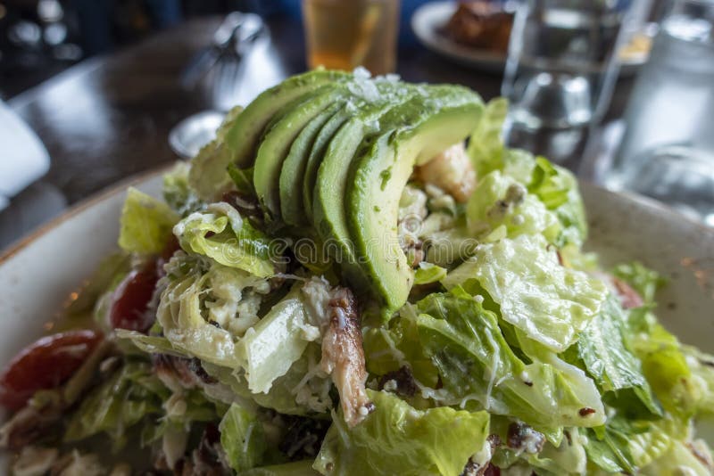 View of a decadent, Dungeness crab and avocado salad on a white and gold plate inside an upscale restaurant. A decadent, Dungeness crab and avocado salad on a