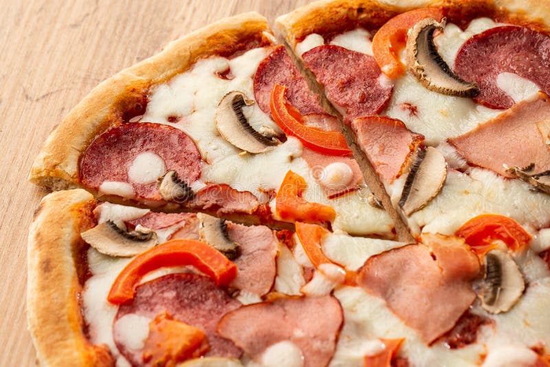 Top view of delicious Capricciosa Pizza on wooden table. Ingredients peeled tomato, cheese, ham, mushrooms, salami. stock image Top view of delicious Capricciosa Pizza on wooden table. Ingredients peeled tomato, cheese, ham, mushrooms, salami. stock image