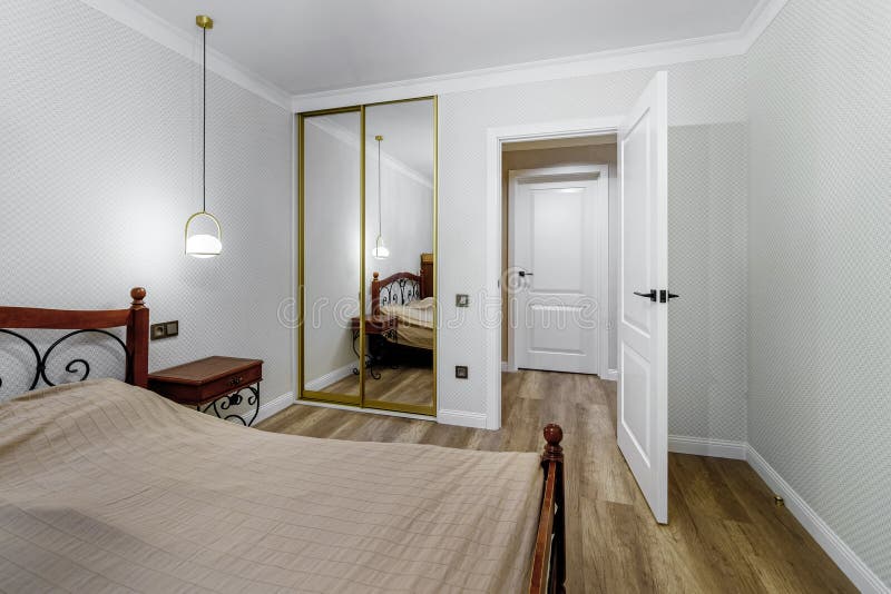 View of the Door and Wardrobe with a Huge Mirror in a Modern Bedroom