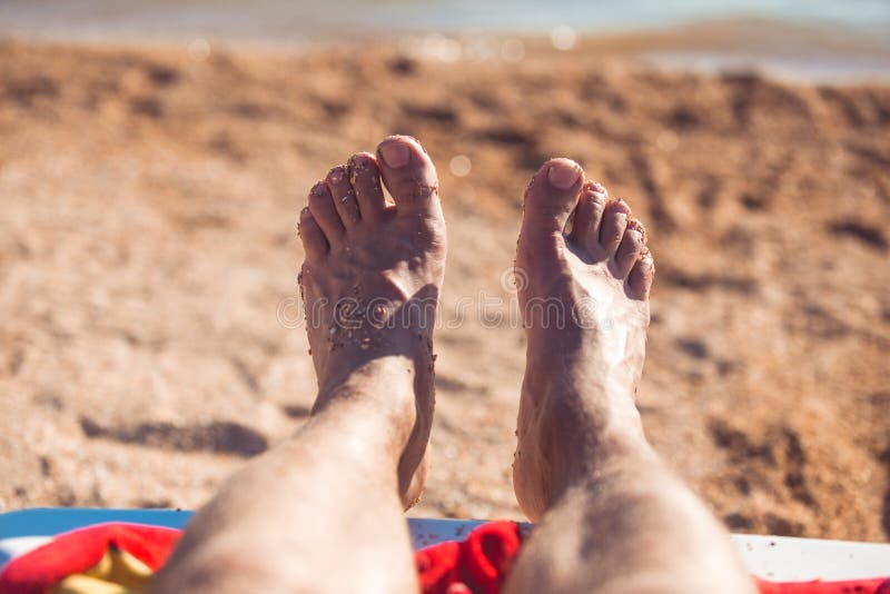View of feet of man which are covered with sand on a beach stock images View of feet of man which are covered with sand on a beach stock images