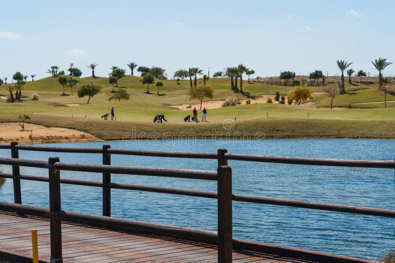 View of a golf course on the Costa Blanca with lake, wooden bridge and golfers on a summer day