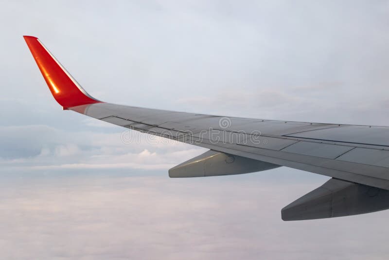 View of the gray sky from the height of flight above the clouds from the window of the plane in the bright sun. part of an airplane wing in the frame. Airplane height stock images, royalty-free photos and pictures