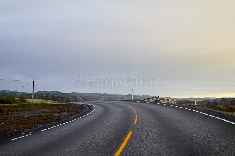 View on grey road, yellow surise and dramatic clouds from the car front window in early mourning. Driving car during sunshine in