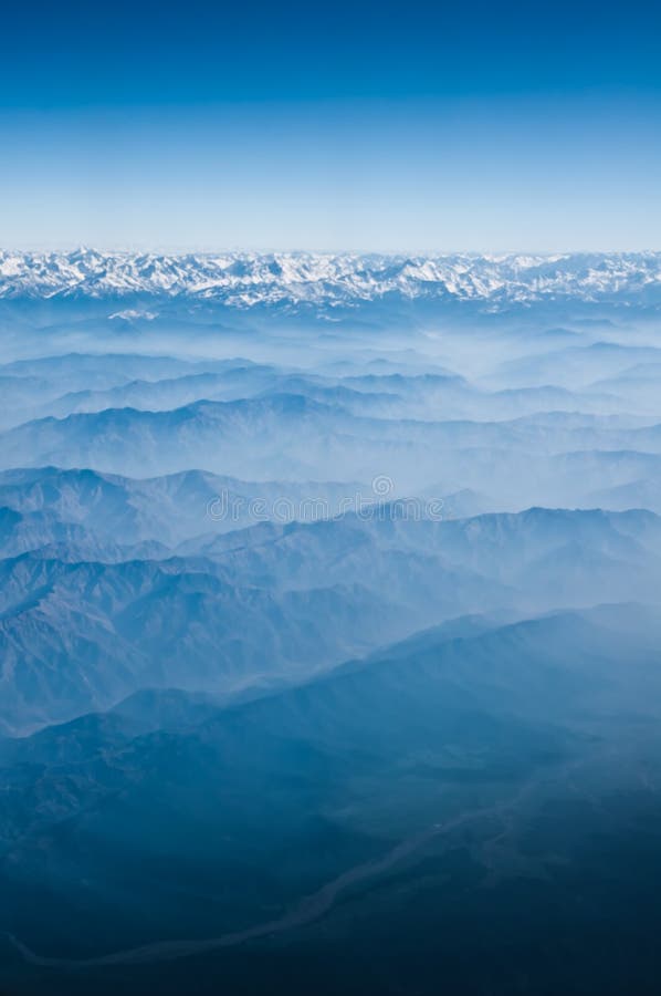 View from the height of the Himalayan mountains from an airplane in the early morning, a landscape in blue colors. blue mountains and foothills under us. Airplane height stock images, royalty-free photos and pictures