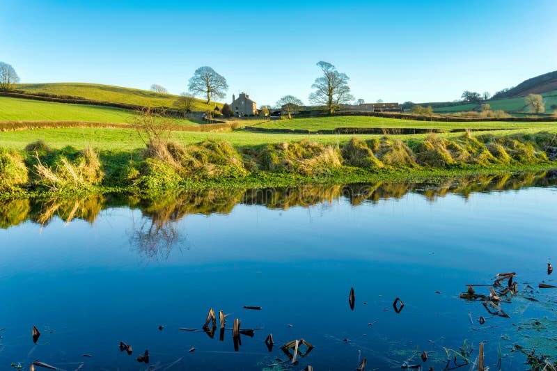 A view of the Lancaster canal with a farm house, bordered by two trees