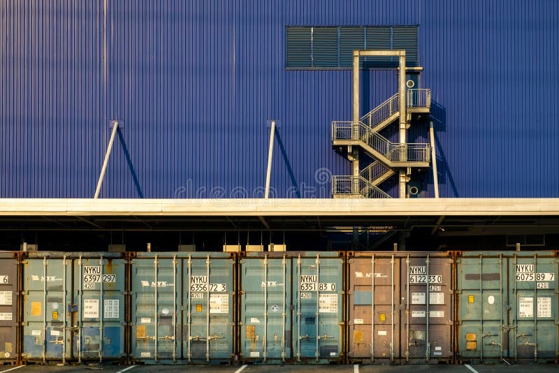 View of many shipping containers doors with fire escape background.