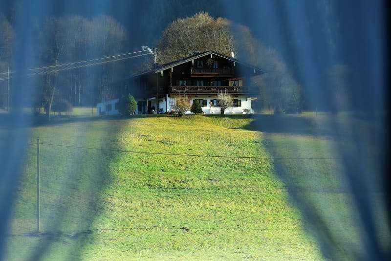 Small house at the mountain seen through the curtains of my window